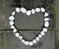 Heart of stone made of small white stones on the dark stone background