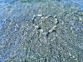 Heart of stones on the sea bottom under water. Background of pebbles and waves. Royalty Free Stock Photo