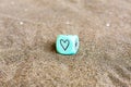 Heart and sun weather symbols on sides of blu plastic cube. Funny gambling dice on sand. Saint Valentines concept. Love