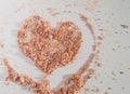 Heart symbol drawn on the scattered powder on a white background