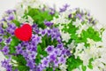 Heart, symbol of love in a bouquet small flowers.