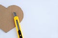 Heart symbol made of brown cardboard with jagged edges and a clerical knife