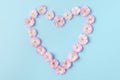 Heart symbol made of pink blossoming spring flowers on blue background. Love concept. Flat lay. Valentines day Royalty Free Stock Photo