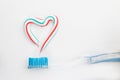 The heart symbol is made from a three-color toothpaste and is located above the toothbrush Royalty Free Stock Photo