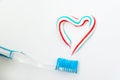 The heart symbol is made from a three-color toothpaste and is located above the toothbrush Royalty Free Stock Photo