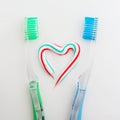 The heart symbol is made from a three-color toothpaste and is located between two toothbrushes Royalty Free Stock Photo