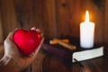 The heart symbol on a woman`s hand A candle lit up the scriptures. Pray for God`s blessing with faith in His power, thoughts of Royalty Free Stock Photo