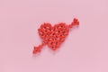 A heart was embroidery by arrow shape of medicine pills on pink background.