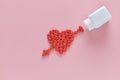 A heart was embroidery by arrow shape of medicine pills pouring out of white bottle on pink background. Concept of Valentine`s Day Royalty Free Stock Photo