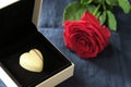 Chocolate heart in jewelry box and red rose on dark blue background Royalty Free Stock Photo