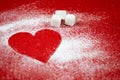 Heart of white powdered sugar on a red background