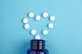 Heart of white tablets spilling out of package, Close up pills spilling out of pill bottle on blue background. Medicine, medical Royalty Free Stock Photo