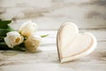 Heart of wood and tulips on a white painted wooden background, r