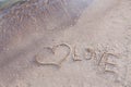Heart and word LOVE written on beach sand Royalty Free Stock Photo