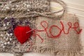 Heart of yarn in cloth and dried flowerson on wooden background