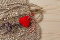 Heart of yarn in cloth and dried flowerson on wooden background