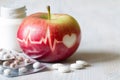 Heartbeat line on red apple and pills, healthy heart diet concept