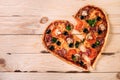 Heartbreak shaped pizza with tomatoes and mozzarella for Valentines Day on vintage black background. Food concept of