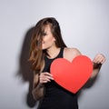 Heartbreaker. Temptress. Seductive woman. Portrait of amazing young fashion woman posing at studio with red heart. Love. Valentine Royalty Free Stock Photo