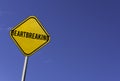 Heartbreaking - yellow sign with blue sky background