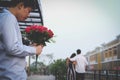 Heartbroken man holding bouquet of red roses feeling sad while s Royalty Free Stock Photo