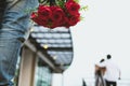 Heartbroken man holding bouquet of red roses feeling sad while s Royalty Free Stock Photo