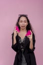 A heartbroken young asian woman wails, holding a separated heart shape prop. Isolated on a pink background Royalty Free Stock Photo