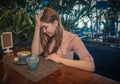 Heartbroken young lady is sitting in cafe and thinking regretfully