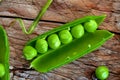 Hearthy fresh green peas and pods on rustic wooden background.