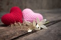 Red and pink knitting hearts with Millingonia on the wooden rough table. Background of the rock wall. Sun light shines on the fram