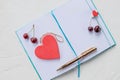 Hearts and cherry. Dreaming theme about love. An open notebook is on a white background.wooden red heart, a declaration Royalty Free Stock Photo