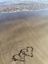 Hearts painted on the beach with water