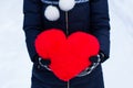 Heartshape pillow in woman's hands at winter day.