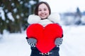 Heartshape pillow in woman's hands at winter day.