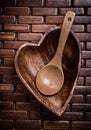 Heartshaped wood bowl and spoon on wooden backcloth top view