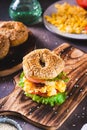 Hearty bagel burger with scramble egg, bacon, cheese, tomato and lettuce vertical view Royalty Free Stock Photo