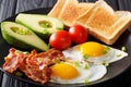 Hearty breakfast: fried eggs with bacon, avocado, toast and toma Royalty Free Stock Photo