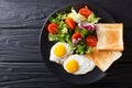 hearty breakfast: fried eggs with fresh vegetable salad and toast close-up. horizontal top view Royalty Free Stock Photo