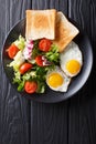 hearty breakfast: fried eggs with fresh vegetable salad and toast close-up. vertical top view Royalty Free Stock Photo