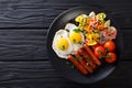 hearty breakfast: fried eggs, sausages, farfalle pasta and tomatoes close-up. Horizontal top view Royalty Free Stock Photo