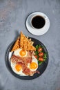 Hearty breakfast of scrambled eggs with bacon, waffles, a salad of greens and tomatoes and a cup of aromatic black coffee Royalty Free Stock Photo