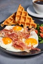 Hearty breakfast of scrambled eggs with bacon, waffles, a salad of greens and tomatoes and a cup of aromatic black coffee Royalty Free Stock Photo