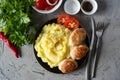 A hearty dinner for the family: Mashed potatoes, pork cutlets, slices of tomatoes on a plate on a gray background. Top