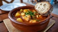 Hearty fish stew with bread in a rustic clay bowl on a table. Royalty Free Stock Photo