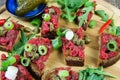 Hearty hefty german snack: isolated wood plate with roasted beef tatar garlic bread, spring onions, capers, pickled cucumbers Royalty Free Stock Photo