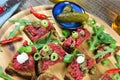 Hearty hefty german snack: isolated wood plate with roasted beef tatar garlic bread, spring onions, capers, pickled cucumbers Royalty Free Stock Photo