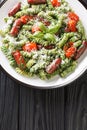 Hearty pasta dish with Genovese pesto, Sausage, Tomatoes and parmesan closeup on the plate on the table. Vertical top view Royalty Free Stock Photo