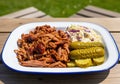 Hearty plate of slow cooked pulled pork with coleslaw and pickles on rustic table Royalty Free Stock Photo