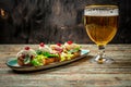 Hearty snack with different kinds of spreads on farmhouse bread served with a fresh yeast wheat beer on an old wooden table.