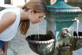 Heat waves concept. Portrait of young woman hydrates herself drinking water from a fountain during a summer hot day